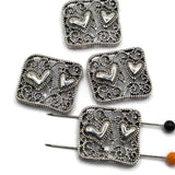 Platinum silver filigree 2 hole slider beads with romantic raised hearts and intricate open scrollwork. Decorative silver focal beads for double strand bracelets, seed bead jewelry, bead weaving, necklace making, DIY bracelet designs, and handmade jewelry.