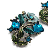 Blue Zircon rhinestone floral slider beads in an antique gold or antique brass finish with colorful blue and teal enamel detailing. These 2 hole focal beads add vibrant sparkle to DIY bracelets, necklaces, bead weaving, multi-strand jewelry, and botanical jewelry designs. Pair with crystals, gemstones, pearls, or seed beads for beautiful handmade jewelry.