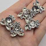 Clear crystal 2 hole slider beads with a sparkling floral-inspired arrangement of round and marquise rhinestones in a platinum silver tone setting. These dimensional focal beads are beautiful jewelry making supplies for double strand bracelets, seed bead projects, bead weaving, necklaces, and statement jewelry. The brilliant clear stones reflect light from multiple angles while the neutral silver finish makes them easy to incorporate into almost any handmade jewelry color palette.