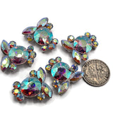 High-quality Clear AB crystal focal beads featuring large round rhinestones surrounded by sparkling marquise and smaller round stones. These platinum silver 2 hole slider beads create dramatic rainbow reflections of aqua, blue, pink, purple, green, and gold. Beautiful for double strand bracelets, necklaces, bead weaving, seed bead jewelry, wedding jewelry, dance accessories, and handmade statement pieces, these Aurora Borealis beads provide brilliant sparkle from every angle.