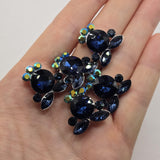 Platinum silver crystal slider beads featuring large Montana Blue faceted rhinestones surrounded by deep blue and Clear AB accent crystals. These decorative multi-hole focal beads add rich navy color, dimensional texture, and brilliant sparkle to bracelets, necklaces, bead weaving, and seed bead jewelry. Hidden loops on the back make them especially versatile for double strand and multi-strand jewelry designs, DIY bracelet making, and elegant handmade accessories.