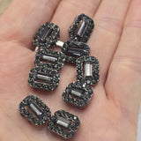 These gunmetal 2 hole slider beads combine jet and hematite rhinestones for a rich, dark metallic appearance. A faceted rectangular center stone creates a striking focal point while smaller coordinating rhinestones surround the edge with smoky sparkle. Designed for double strand bracelets and multi-strand jewelry, these beads also work beautifully in bead weaving, necklaces, and creative DIY jewelry projects. Their charcoal, black, and silver tones complement nearly any jewelry color palette.
