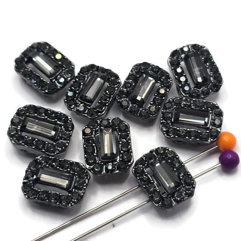 These jet and hematite rhinestone 2 hole slider beads feature a faceted rectangular center surrounded by sparkling coordinating crystals in a dark gunmetal setting. The combination of smoky gray, black, and metallic tones creates sophisticated sparkle without bright color. Perfect for double strand bracelets, bead weaving, necklaces, and statement jewelry, these crystal focal beads pair beautifully with black beads, gemstones, seed beads, silver accents, and other jewelry making supplies.