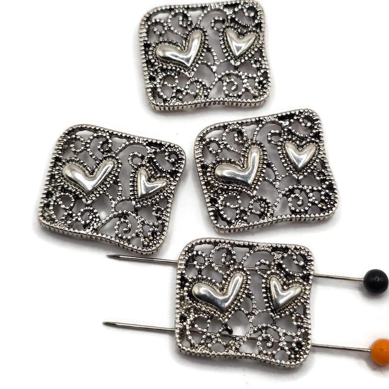 Platinum silver filigree heart 2 hole slider beads with intricate openwork scroll detailing and raised heart accents. Decorative metal focal beads for double strand bracelets, bead weaving, seed bead jewelry, necklaces, DIY bracelet designs, and handmade jewelry making.