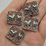 Decorative heart 2 hole slider beads in platinum silver tone with detailed filigree scrollwork and an open metal design. Use these silver focal beads for DIY bracelets, double strand designs, bead weaving, seed bead jewelry, necklaces, and romantic handmade jewelry projects.