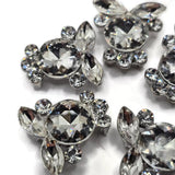 Clear rhinestone 2 hole focal beads with a dramatic cluster of faceted crystals set in bright platinum silver tone metal. Round and marquise-shaped rhinestones create a dimensional floral appearance with incredible sparkle from every angle. Perfect for bracelet making, double strand jewelry, necklaces, bead weaving, seed bead designs, bridal jewelry, and handmade statement pieces, these sparkling slider beads bring a polished boutique-quality look to DIY jewelry projects.