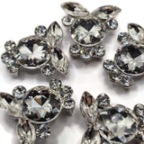 Sparkling clear crystal slider beads featuring a large round rhinestone accented with marquise-cut and smaller round rhinestones in a platinum silver tone setting. These 2 hole focal beads add brilliant light reflection to double strand bracelets, necklaces, seed bead jewelry, and bead weaving projects. Their versatile clear crystal design coordinates with virtually any color palette, making them beautiful jewelry making supplies for elegant, bridal, formal, and statement jewelry.