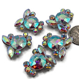 Sparkling Clear AB rhinestone focal beads in a cool platinum silver metal tone featuring a dimensional cluster of faceted crystals. Large round stones, marquise rhinestones, and smaller crystal accents create beautiful Aurora Borealis flashes of turquoise, pink, purple, green, blue, and gold. These 2 hole slider beads are perfect for bracelet making, necklaces, bead weaving, seed bead designs, bridal jewelry, and colorful DIY jewelry projects.