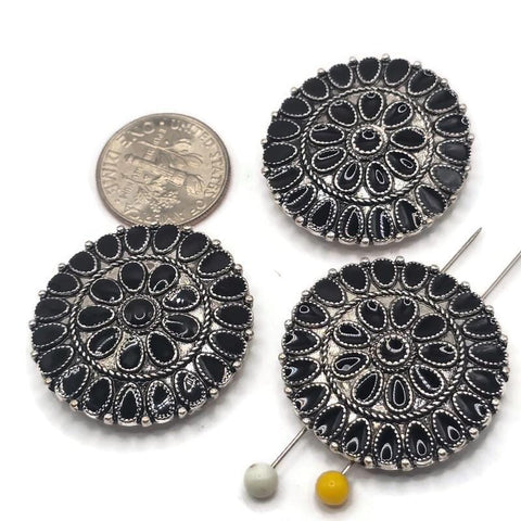 Large round 2 hole slider bead with glossy black enamel detailing and an antique platinum silver finish. The intricate western-inspired medallion pattern features repeating teardrop shapes and dimensional metalwork, creating a bold focal bead for handmade bracelets, necklaces, hat bands, bead weaving, and multi-strand jewelry designs.
