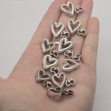 Double heart 2 hole slider bead featuring a large open heart and smaller coordinating heart in mixed soft gold and silver metal finishes. A beautiful focal component for bracelets, bead weaving, multi-strand jewelry, romantic designs, and handmade gifts.