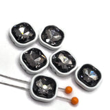 Smoky black diamond rhinestone slider beads in white enamel metal settings for bracelet making and handmade jewelry. The large faceted center stones create reflective gray and charcoal sparkle, while the square white frames provide striking contrast. Each 2-hole bead includes two stringing holes on both sides to accommodate double-strand and multi-strand designs. Decorative focal components for beaded bracelets, necklaces, jewelry making at home, bead weaving, and DIY jewelry projects.
