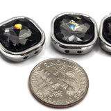 Faceted Black Diamond 2 hole slider beads surrounded by smooth platinum silver metal settings with a stainless-steel-colored appearance. The large smoky rhinestones catch the light with dramatic charcoal and silver reflections, creating sophisticated focal points for handmade jewelry. Two holes on each side allow these square connector beads to stay neatly positioned in double-strand bracelets, necklaces, bead weaving, cuffs, multi-strand jewelry, and other beading and bracelet-making projects.