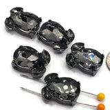 Black Diamond rhinestone jewelry connectors set in dark gunmetal plated metal with two hidden stringing loops on the back. These 20 mm statement slider beads feature large smoky gray teardrop crystals accented by smaller faceted stones for dimensional shine and reflective sparkle. Decorative 2 hole focal beads for beaded bracelets, multi-strand jewelry, necklaces, bead weaving, dramatic accessories, artisan jewelry, and creative DIY bracelet-making projects.