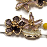 Bright gold enamel flower beads featuring layered botanical designs for handmade bracelets and jewelry making. Each 2 hole slider bead combines a soft pink pointed-petal flower, rounded deep plum bloom, and creamy ivory leaf for dimensional floral detail. Approximately 7.5 mm between the stringing holes makes these 26 mm focal beads useful for bead weaving, double-strand jewelry, necklaces, cuffs, and botanical-inspired designs.