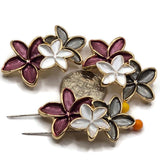 Large floral 2 hole slider beads with plum, white, and smoky gray enamel flowers outlined in bright gold metal. Three connected five-petal blooms create an elongated 37.5 mm botanical focal with approximately 10 mm between the stringing holes. Decorative jewelry-making components for double-strand bracelets, bead weaving, cuffs, necklaces, statement jewelry, garden-inspired designs, elegant handmade accessories, and creative jewelry making at home.