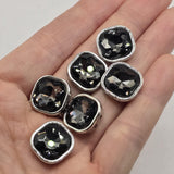 Square 2-hole slider beads with sparkling black diamond faceted rhinestones set inside white enamel metal frames. The smoky gray stones reflect light from multiple angles while the crisp white enamel creates a bold contrasting border. Two holes on each side allow these focal beads to work beautifully in double-strand bracelets, necklaces, bead weaving, and other handmade jewelry designs. Decorative jewelry findings for beaders, bracelet making, and DIY jewelry projects.