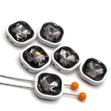Black diamond rhinestone 2-hole slider beads featuring large faceted stones surrounded by smooth white enamel metal frames. These square jewelry-making beads have two holes on each side to help keep them positioned in bracelet, necklace, and multi-strand designs. The smoky black diamond crystal centers add dramatic sparkle against the crisp white enamel finish. Decorative focal beads for beaded bracelets, handmade jewelry, bead weaving, and DIY jewelry-making projects.