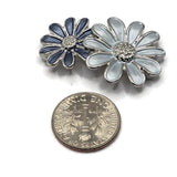Platinum silver 2 hole slider beads with decorative double-daisy flowers and coordinating blue enamel petals. These floral jewelry components feature a stainless-steel-colored metal finish with textured flower centers and varying shades of pale blue, silvery gray-blue, and darker slate blue. Designed for double-strand bracelets and multi-strand jewelry, these unique focal beads work beautifully with bead weaving, handmade necklaces, botanical jewelry, DIY bracelets, and other beading projects.