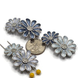 Blue enamel flower slider beads featuring double-daisy designs in a cool platinum silver finish for handmade jewelry making. This mixed package includes three coordinating floral color combinations with light blue, gray-blue, and deeper blue enamel petals surrounding textured silver centers. Two-hole construction makes these decorative focal beads ideal for double-strand bracelets, bead weaving, necklaces, multi-strand jewelry designs, botanical jewelry, spring accessories, and creative projects