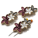 Bright gold floral 2 hole slider beads featuring three connected enamel flowers in rich plum, pearly white, and smoky gray. Each large 37.5 mm focal bead has sculpted five-petal flowers with polished gold outlines and textured enamel detailing. Two stringing holes approximately 10 mm apart make these statement jewelry components ideal for double-strand bracelets, bead weaving, necklaces, cuffs, and botanical jewelry designs.
