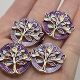 Beautiful Tree of Life 2 Hole Slider Beads featuring colorful purple, lavender, light blue, and white enamel leaves surrounded by a bright reflective gold finish. These round jewelry focal beads feature intricate openwork tree designs with decorative textured borders. Perfect for handmade bracelet designs, necklace making, bead weaving, and unique jewelry creations. Beautiful jewelry making supplies for beginners and experienced jewelry designers creating colorful