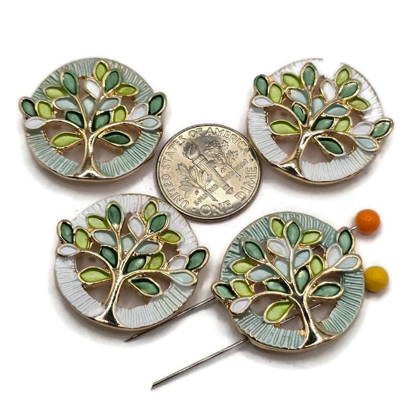 Beautiful pastel green Tree of Life 2 Hole Slider Beads featuring sage green, soft mint, pale seafoam, lime green, and white enamel leaves outlined in bright reflective gold. These round jewelry focal beads showcase complementary pale mint and pearly white textured circular backgrounds with intricate openwork tree designs. Perfect jewelry making supplies for handmade bracelets, necklace designs, multi-strand jewelry, and bead weaving projects inspired by delicate botanical colors and nature.