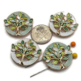 Beautiful pastel green Tree of Life 2 Hole Slider Beads featuring sage green, soft mint, pale seafoam, lime green, and white enamel leaves outlined in bright reflective gold. These round jewelry focal beads showcase complementary pale mint and pearly white textured circular backgrounds with intricate openwork tree designs. Perfect jewelry making supplies for handmade bracelets, necklace designs, multi-strand jewelry, and bead weaving projects inspired by delicate botanical colors and nature.