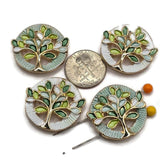 Stunning round Tree of Life Slider Beads featuring bright reflective gold branches surrounded by delicate sage green, mint, seafoam, lime, and white enamel leaves. These decorative jewelry components include coordinating pastel green and pearly white circular backgrounds with intricate textured borders. Wonderful focal beads for handmade bracelets, beaded necklaces, multi-strand jewelry, and creative bead weaving.