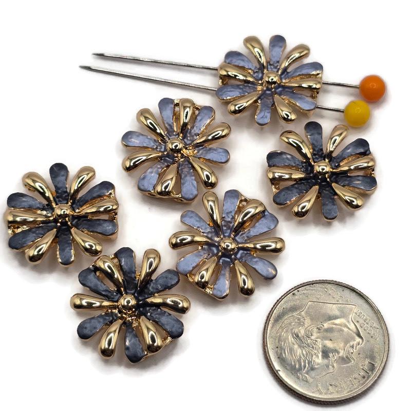 Beautiful gold flower focal beads featuring contrasting dusty blue and deep charcoal blue enamel petals with delicate textured surfaces. Each round floral jewelry component showcases alternating highly reflective gold petals and colorful enamel accents surrounding a raised gold center. These 2 Hole Slider Beads are perfect for handmade jewelry designs, multi-strand bracelets, necklace making, and bead weaving projects.