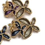 Elegant bright gold flower jewelry making beads featuring layered floral designs with contrasting enamel petals in charcoal gray, deep burgundy, smoky champagne, purple, and navy blue. Each 2 Hole Slider Bead showcases overlapping dimensional flowers with polished gold borders and delicate metallic floral accents. Beautiful jewelry components for bracelet making, necklace designs, bead weaving, and handmade accessories.