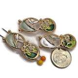 Beautiful bright gold jewelry focal beads featuring an abstract botanical design with two connected oval shapes and colorful enamel leaf accents. Soft mint green, pale aqua, pearly ivory, forest green, and fresh lime create a coordinated nature-inspired color combination. These decorative 2 Hole Slider Beads are perfect for bracelet making, necklace designs, bead weaving, and handmade jewelry projects. Unique jewelry findings for elegant floral accessories and artisan creations.
