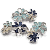Elegant light blue and dark blue flower jewelry making beads featuring layered floral clusters with softly textured enamel petals and highly polished bright silver metalwork. The coordinated package includes aqua blue, navy, and pearly ivory blossoms with raised metallic flower centers. These decorative 2 Hole Slider Beads are ideal for bracelet making, necklace designs, bead weaving, and creative handmade jewelry.