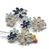 Decorative navy blue, cream, and light aqua floral beads featuring three overlapping flowers with contrasting enamel petals and polished bright silver outlines. The larger blossoms showcase pearly ivory enamel and reflective openwork silver petals, while smaller flowers introduce textured dark blue and delicate aqua accents. These 2 Hole Slider Beads are perfect for handmade jewelry designs, double-strand bracelets, necklace making, and bead weaving.