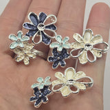 Elegant cream and dark blue flower jewelry-making beads featuring layered floral clusters with pearly ivory petals, textured navy blue blossoms, and delicate light blue accents. Highly reflective bright silver outlines and openwork metallic petals add beautiful dimension to each decorative 2 Hole Slider Bead. Perfect for bracelet making, necklace designs, bead weaving, and handmade accessories. Unique floral focal beads for sophisticated jewelry, botanical themes, and coordinated jewelry sets.