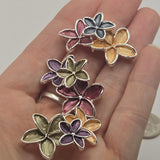 Beautiful bright silver floral 2 Hole Slider Bead featuring three overlapping five-petal flowers in warm peach, rich burgundy, and deep charcoal gray enamel. Each blossom showcases delicately textured petals with polished silver outlines that highlight the dimensional floral arrangement. These decorative jewelry-making components are perfect for handmade bracelets, necklaces, bead weaving, and multi-strand jewelry designs.