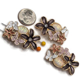 Beautiful bright gold floral butterfly 2 Hole Slider Beads featuring dimensional chocolate brown flowers with sparkling clear rhinestone centers, smaller rose gold flowers, and delicate white and lavender butterflies. Each decorative focal bead includes a shimmering iridescent accent with soft pastel reflections. These unique jewelry-making components are perfect for handmade bracelets, necklaces, bead weaving, botanical jewelry, and garden-inspired accessories featuring elegant floral details.