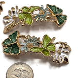 Elegant green butterfly and floral 2 Hole Slider Beads in a polished bright gold finish. Each decorative jewelry component features dimensional emerald green and lime green butterflies with detailed enamel wings, complemented by delicate white and sage green flowers. Textured gold flower centers and openwork metal accents add intricate botanical detail. Beautiful focal beads for double-strand bracelets, necklaces, bead weaving, spring jewelry, and handmade butterfly-themed accessories.