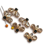 Bright gold light smoked topaz rhinestone 2 hole slider beads arranged on a white background. Each unique fan-shaped floral focal bead features two teardrop-shaped champagne rhinestones, a faceted marquise center stone, and a contrasting dark smoked topaz round rhinestone. Decorative textured gold settings frame the sparkling stones, creating elegant jewelry-making components measuring approximately 22 mm wide and 15 mm tall.