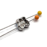 Clear AB butterfly 2 hole slider beads displayed with jewelry-making pins demonstrating their side-drilled construction. Each butterfly features a faceted clear Aurora Borealis stone surrounded by polished platinum silver metal, with approximately 5 mm between the holes. These decorative components help maintain strand spacing in double-strand bracelets, bead weaving, necklaces, and multi-strand handmade jewelry.