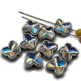 Nine Clear AB butterfly 2 hole slider beads arranged on a white background. Each butterfly features a faceted clear Aurora Borealis stone with beautiful rainbow reflections surrounded by a polished platinum silver metal setting. These small decorative butterfly focal beads measure approximately 11 mm wide and 10.5 mm tall, perfect for handmade bracelets, necklaces, bead weaving, and multi-strand jewelry designs.