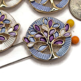 Stunning round Tree of Life Slider Beads featuring bright reflective gold branches surrounded by colorful purple and blue enamel leaves. These decorative jewelry focal beads feature beautiful pearly white and soft blue circular backgrounds with intricate textured borders. Perfect for creating handmade bracelets, beaded necklaces, multi-strand jewelry, and creative bead weaving projects. Beautiful jewelry components for designers who enjoy colorful beads, meaningful symbols, and gold accents.