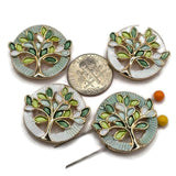 Beautiful gold Tree of Life focal beads featuring soft mint green and pearly white circular backgrounds with decorative textured detailing. Each round bead showcases intricate reflective gold branches and delicate enamel leaves in sage, seafoam, lime green, and white. These 2 Hole Slider Beads are perfect for handmade jewelry designs, multi-strand bracelets, necklace making, and bead weaving.