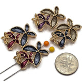 Decorative floral 2 Hole Slider Beads featuring beautiful overlapping flowers with textured enamel petals and reflective bright gold outlines. The assorted color combinations include charcoal gray, smoky champagne, rich burgundy, purple, and deep navy blue accents. Each jewelry focal bead includes a delicate openwork gold flower for additional dimensional detail. Excellent jewelry making components for bracelets, necklaces, bead weaving, handmade gifts.