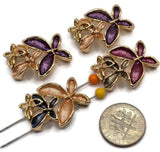 Elegant bright gold flower jewelry making beads featuring layered floral designs with contrasting purple, burgundy, champagne, peach, and charcoal blue enamel petals. Each 2 Hole Slider Bead showcases overlapping dimensional flowers with polished gold borders and delicate metallic floral accents. Beautiful jewelry components for bracelet making, necklace designs, bead weaving, and handmade accessories.