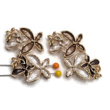 Beautiful gold floral focal beads featuring contrasting champagne brown, ivory white, and deep chocolate brown enamel flowers. Each decorative jewelry component showcases three overlapping blossoms with elongated textured petals, polished gold borders, and delicate openwork metallic flower accents. These 2 Hole Slider Beads are perfect for handmade jewelry designs, multi-strand bracelets, necklace making, and bead weaving. Unique jewelry findings for boutique collections, elegant floral