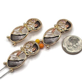 Unique abstract floral 2 Hole Slider Beads showcasing an artistic double-oval design with charcoal gray enamel, delicate champagne leaves, and pearly ivory botanical accents. Highly reflective bright gold metalwork frames the contrasting enamel sections and flowing openwork details. These decorative jewelry components are perfect for handmade bracelets, necklaces, bead weaving, and multi-strand jewelry projects.