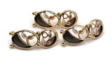 Decorative bright gold jewelry focal beads featuring two connected oval shapes accented with graceful botanical branches, charcoal enamel sections, and small champagne and ivory leaves. The asymmetrical openwork design combines flowing curves, textured enamel details, and polished metallic surfaces. These 2 Hole Slider Beads offer jewelry makers a beautiful alternative to traditional floral beads.