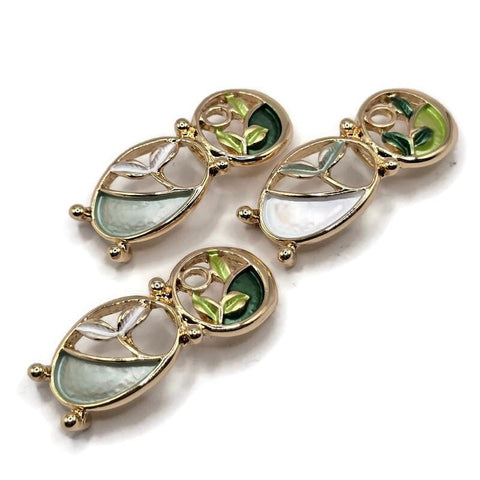 Elegant green and ivory botanical jewelry making beads featuring an artistic double-oval design with polished bright gold outlines and softly textured enamel accents. Delicate leaf details in mint, aqua, forest green, and fresh lime create a beautiful nature-inspired appearance. These 2 Hole Slider Beads are ideal for bracelet making, necklace designs, bead weaving, and creative handmade jewelry. Unique focal beads for garden-inspired accessories, botanical jewelry, and artisan designs.