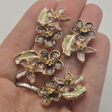 Beautiful gold floral focal beads featuring contrasting smoky chocolate brown and dusty mauve enamel flowers accented with a softly curved ivory leaf. Each decorative jewelry component showcases dimensional five-petal blossoms, raised metallic flower centers, and highly reflective bright gold outlines. These 2 Hole Slider Beads are perfect for handmade jewelry designs, double-strand bracelets, necklace making, and bead weaving.