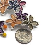 Close-up of a decorative floral 2 Hole Slider Bead featuring a large peach enamel flower, rich burgundy blossom, and smaller charcoal gray flower in a polished bright silver finish. Each five-petal flower displays delicate textured lines and raised metallic borders. The overlapping design creates a beautiful dimensional focal point for handmade jewelry. Unique flower beads for bracelet making, necklaces, bead weaving, botanical jewelry, and elegant artisan accessories.